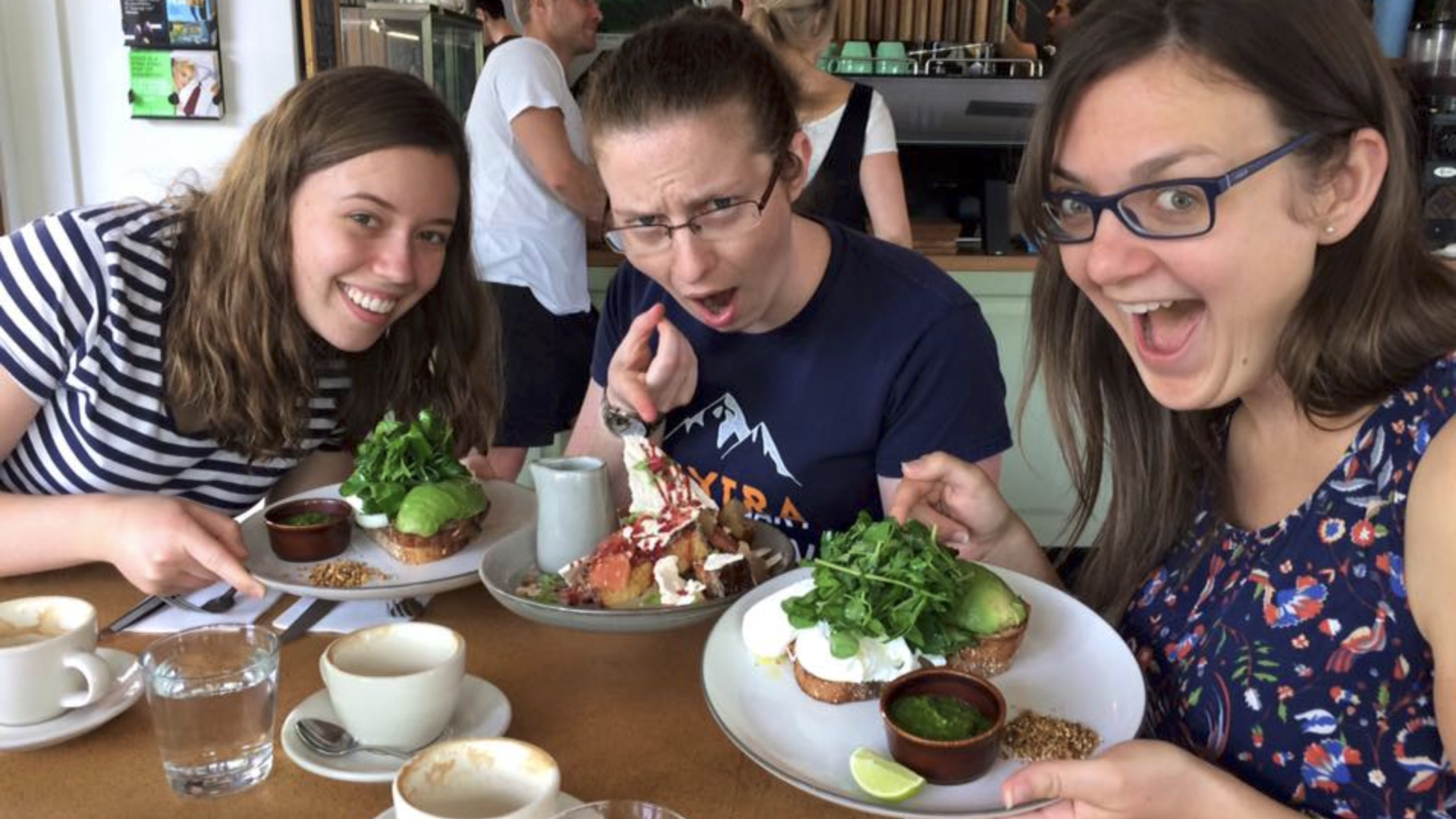 Subject: Three women
Context: Indeterminate or neutral background
Action: The women are licking t...