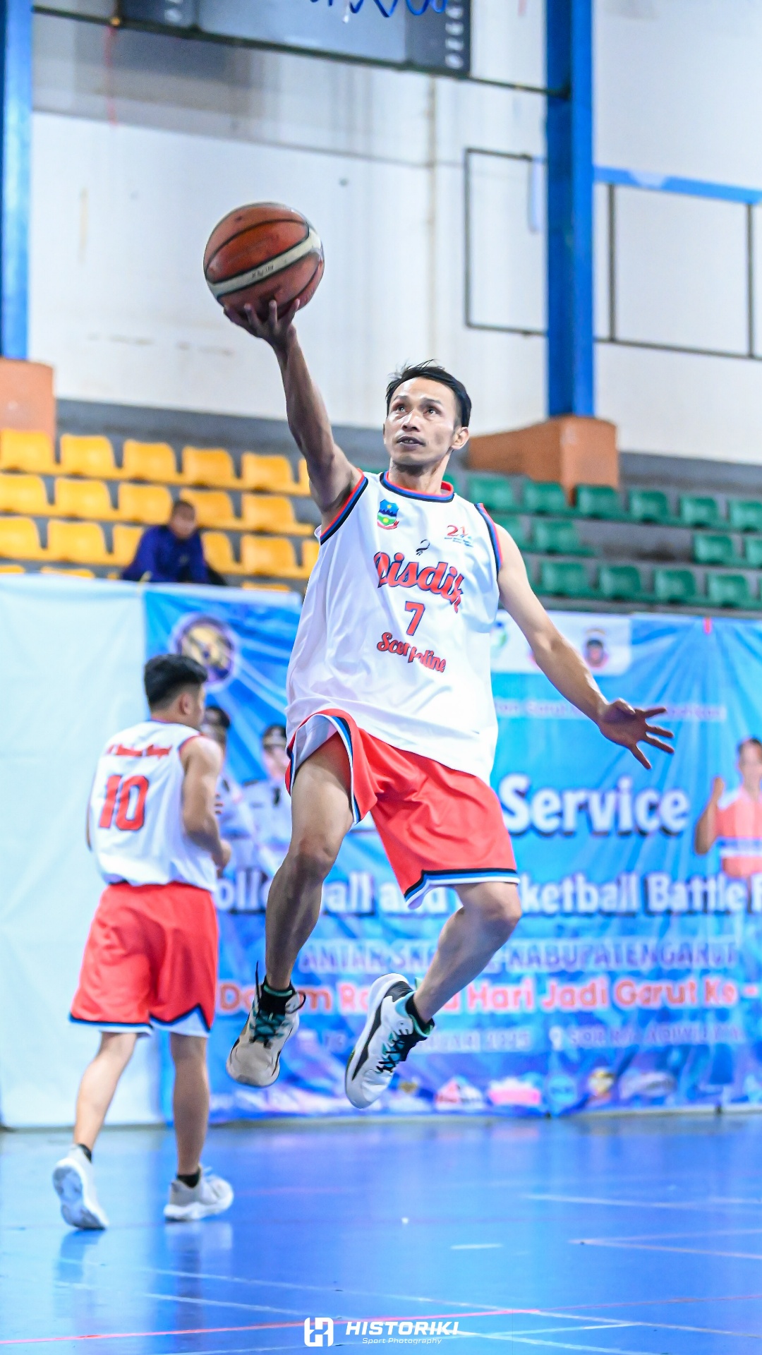 Subjek: Pemain basket dengan tubuh atletis dan ekspresi penuh fokus  
Konteks: Arena basket indoo...