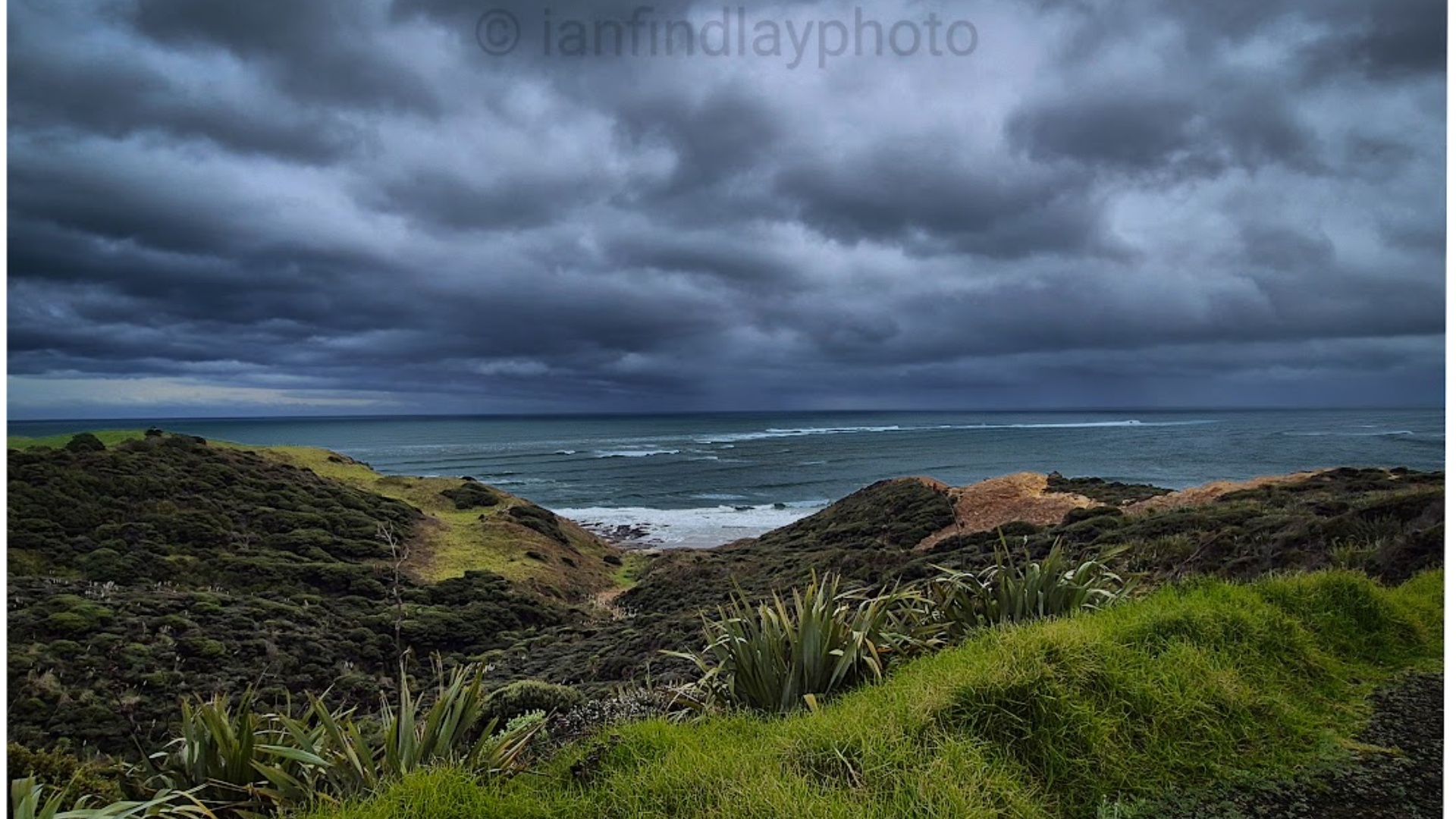 Subject: Ocean waves and incoming clouds  
Context: Open sea with a visible coastline in the dist...