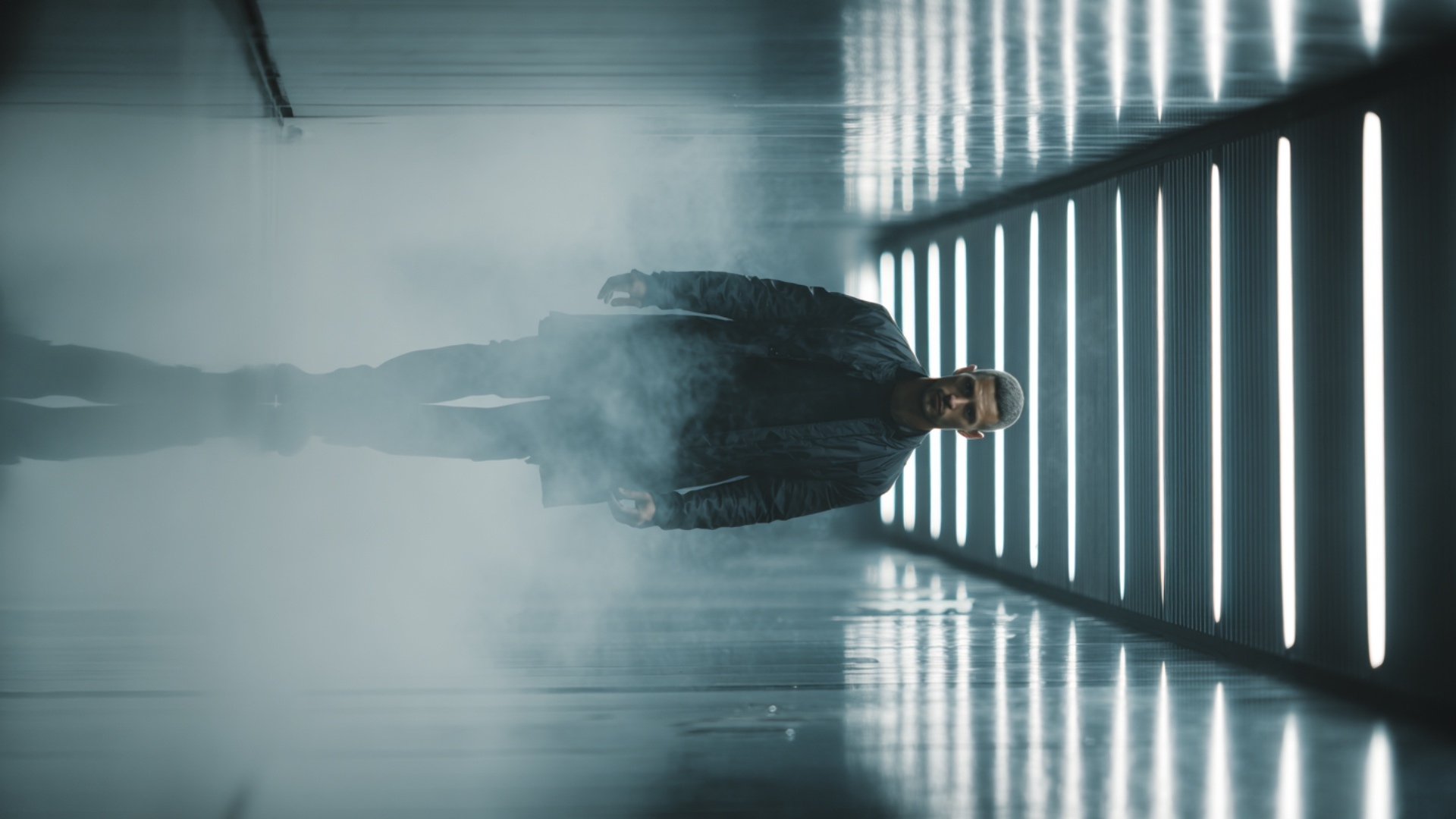 Cinematic walking shot, a confident man walking slowly towards the camera in a dark modern corrid...