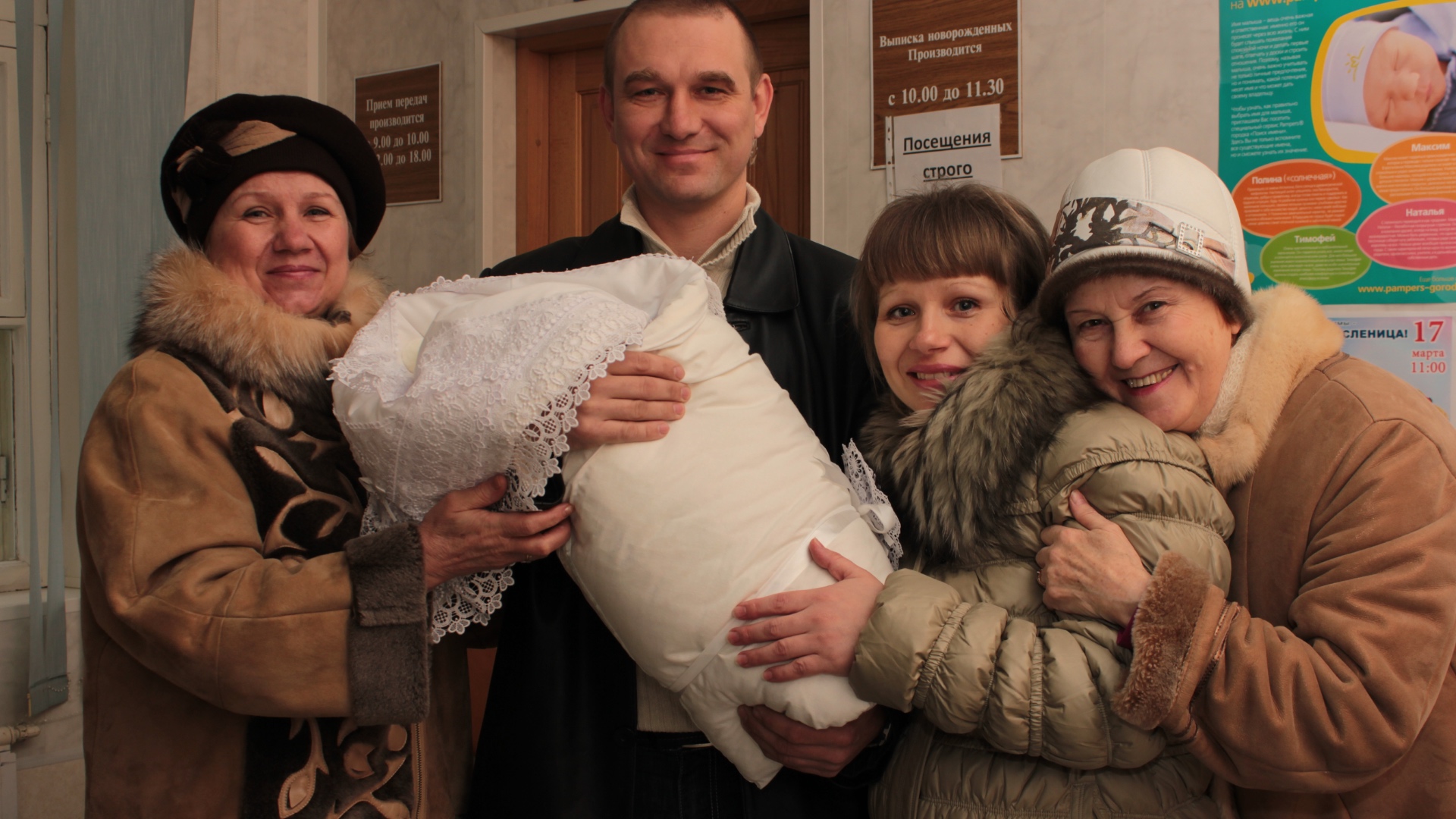 A front-facing medium shot of four adults (men and women) standing together in a maternity hospit...