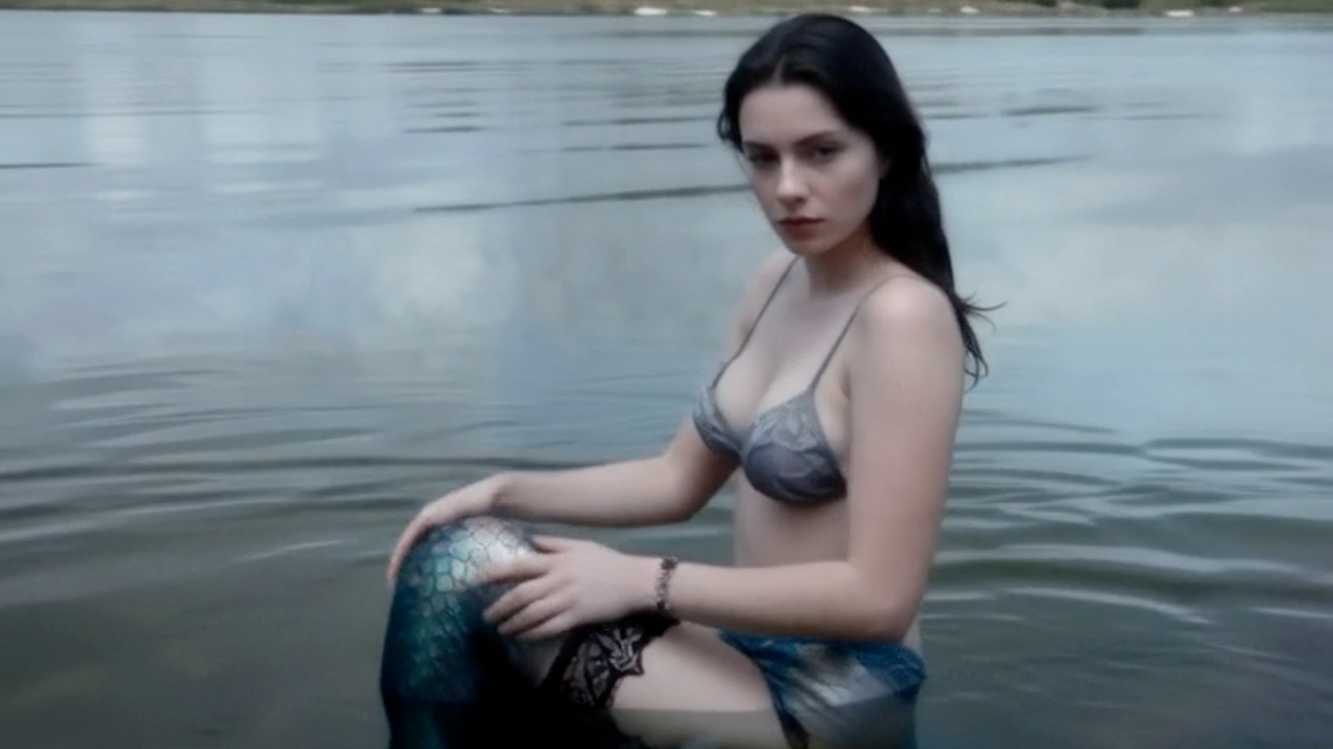 The undulating mermaid glides sensually through the misty lake water.