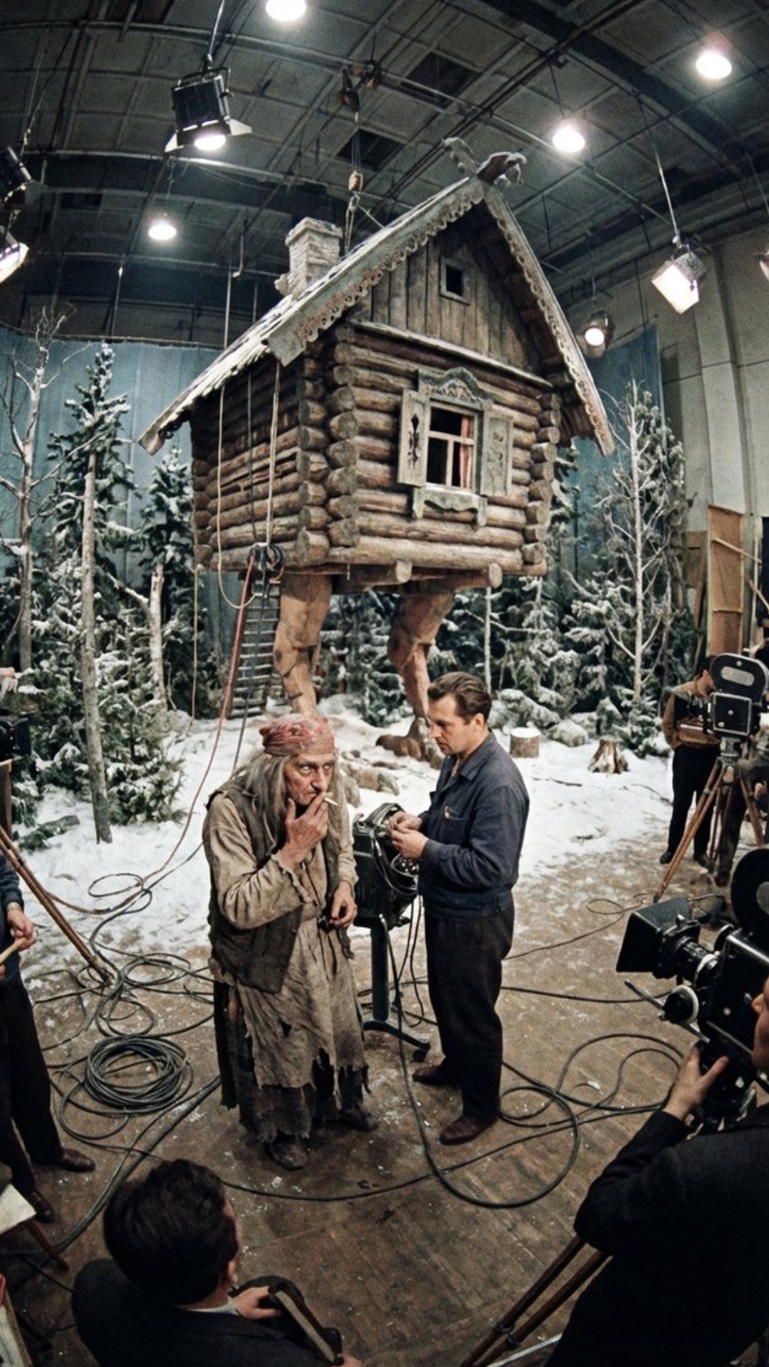 Cinematic shot from Morozko: Baba Yaga smoking a cigarette and talking to a man on a film set, th...