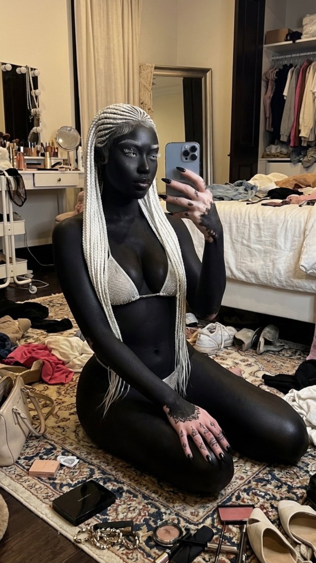 The girl is taking a mirror selfie video. She looks directly into the mirror reflection and lifts...