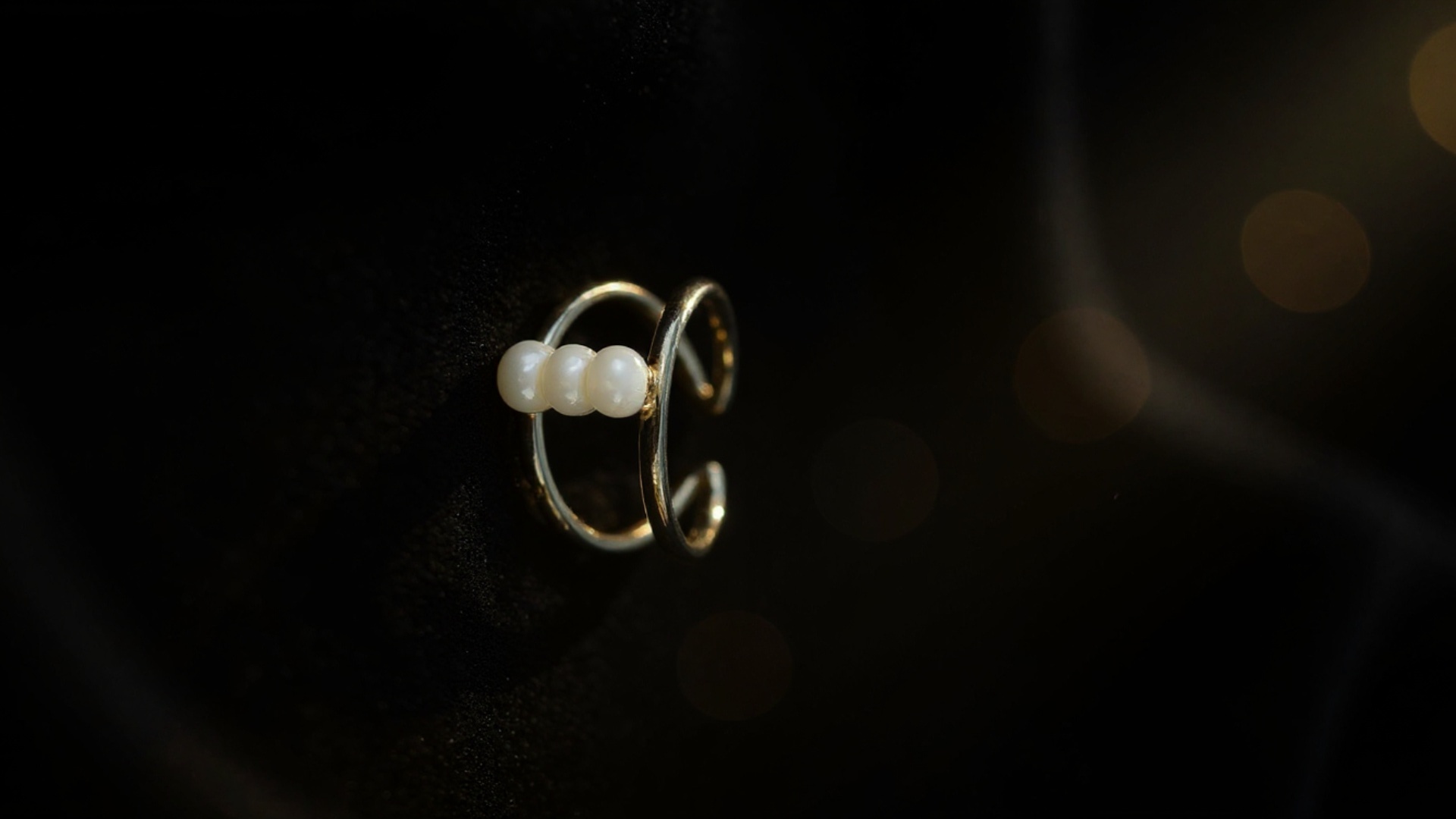 A luxurious close-up of a silver ring with a gemstone resting on deep black velvet fabric. Soft, ...