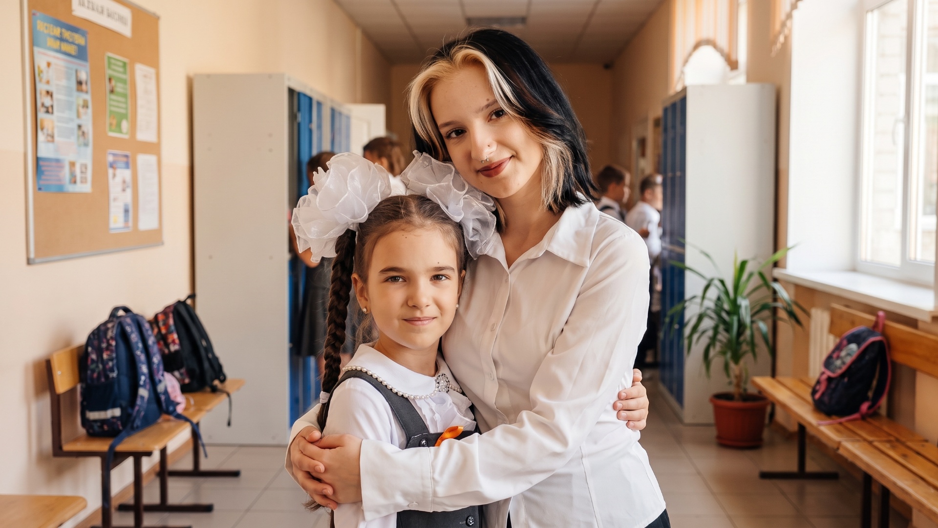 "Animate the combined image of the younger girl and the older girl in a school hallway. Keep thei...