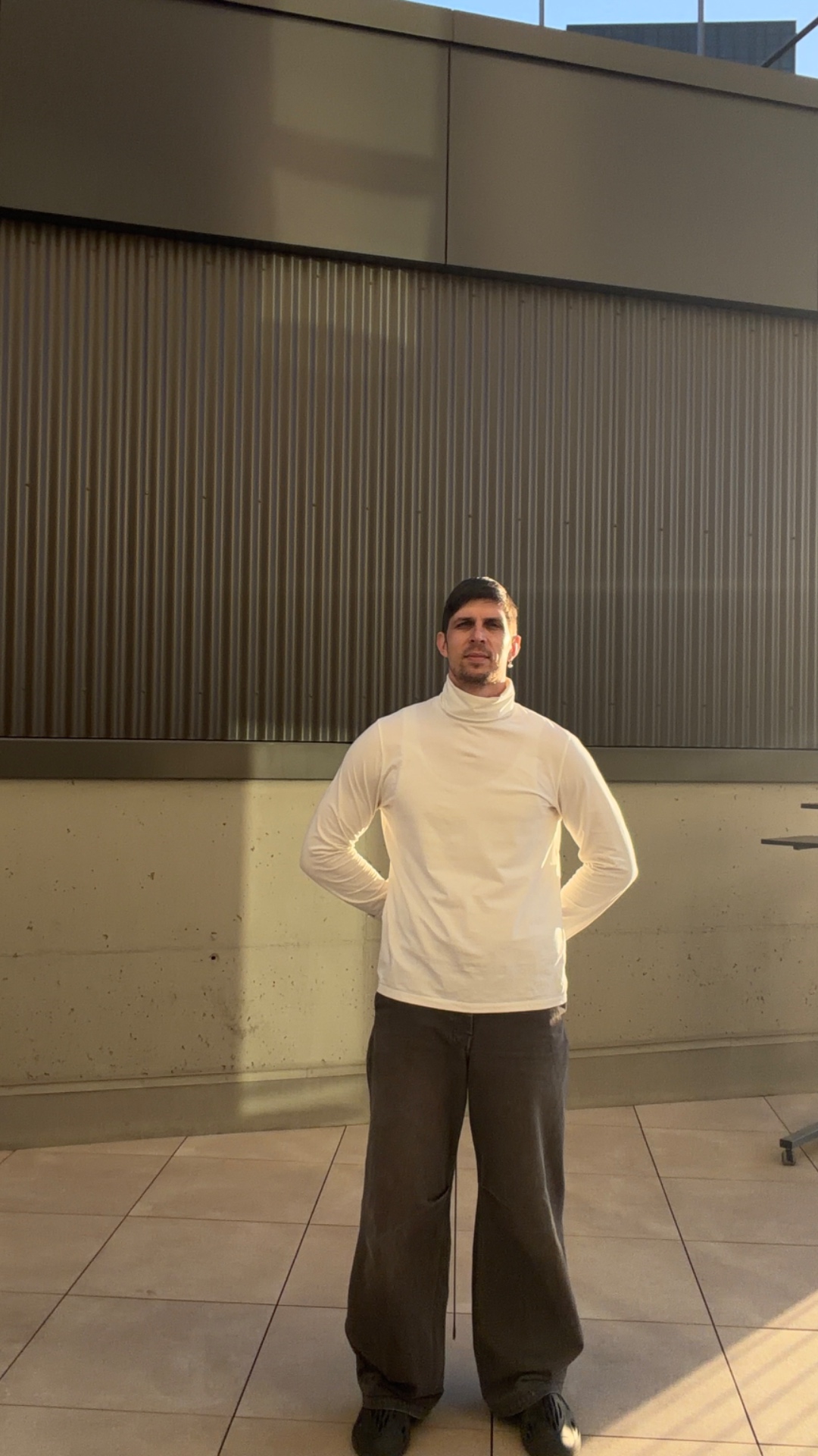 Static camera, rooftop terrace, warm evening sunlight, minimalist cinematic style. A man in white...
