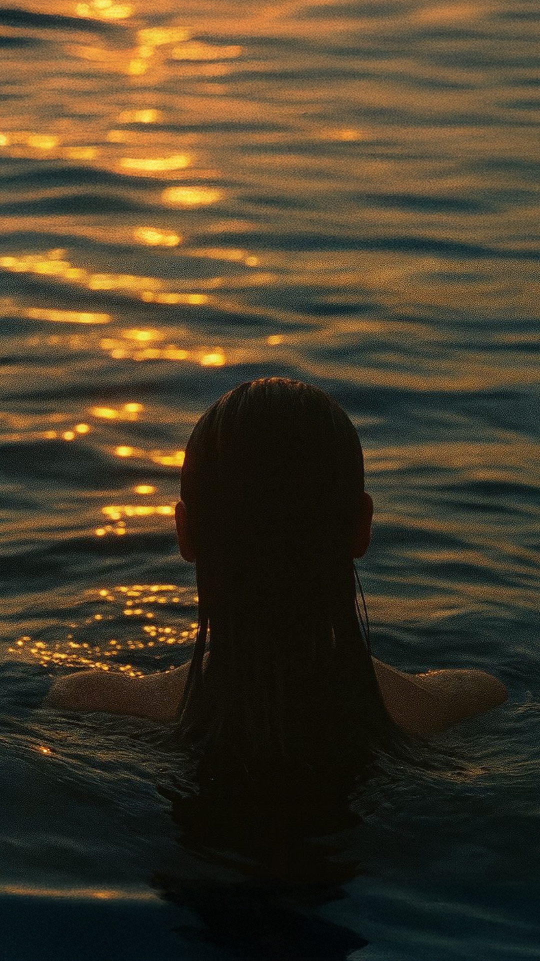 Subject: Woman with wet hair gracefully swimming into the sea, seen from behind  
Context: Calm o...