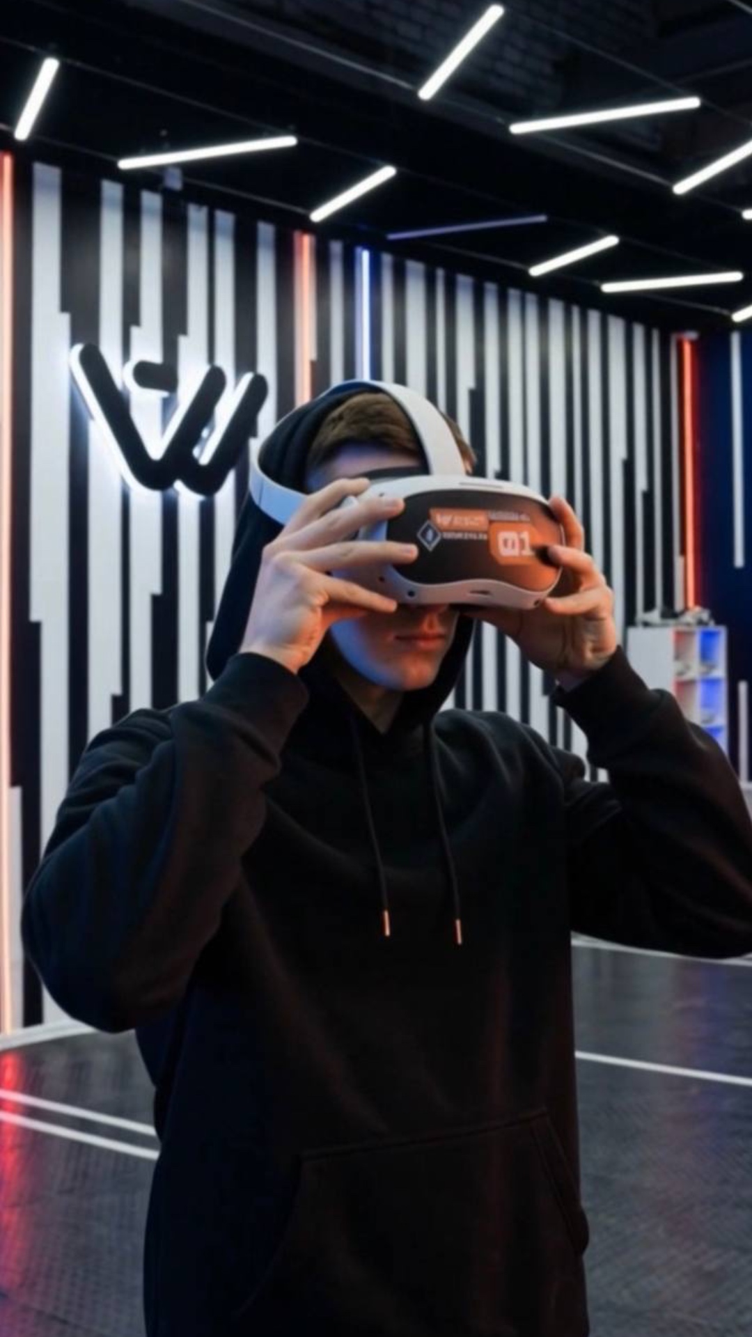 Close-up on a man in a dark room with dim vertical stripes. He slowly puts on a sleek VR headset....