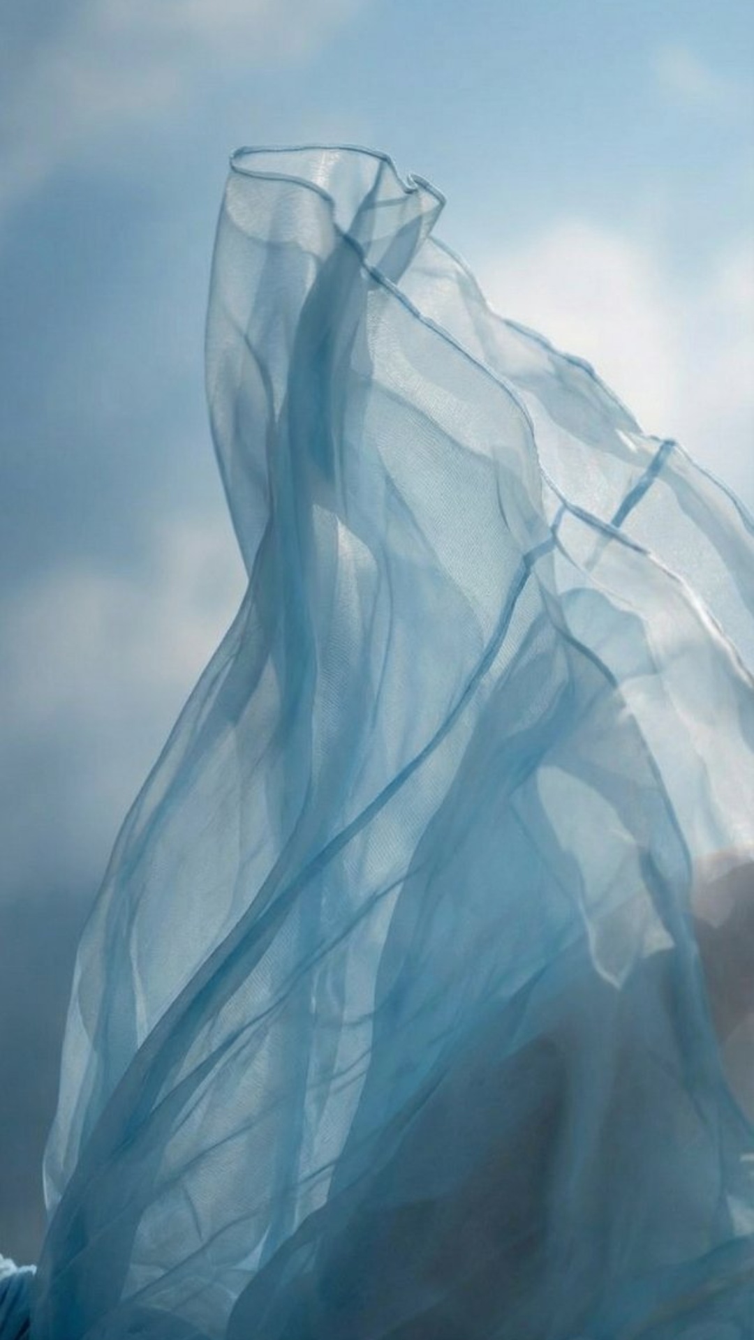 Extreme cinematic close-up of the light blue dress fabric during mid-fall.

The woman continues d...