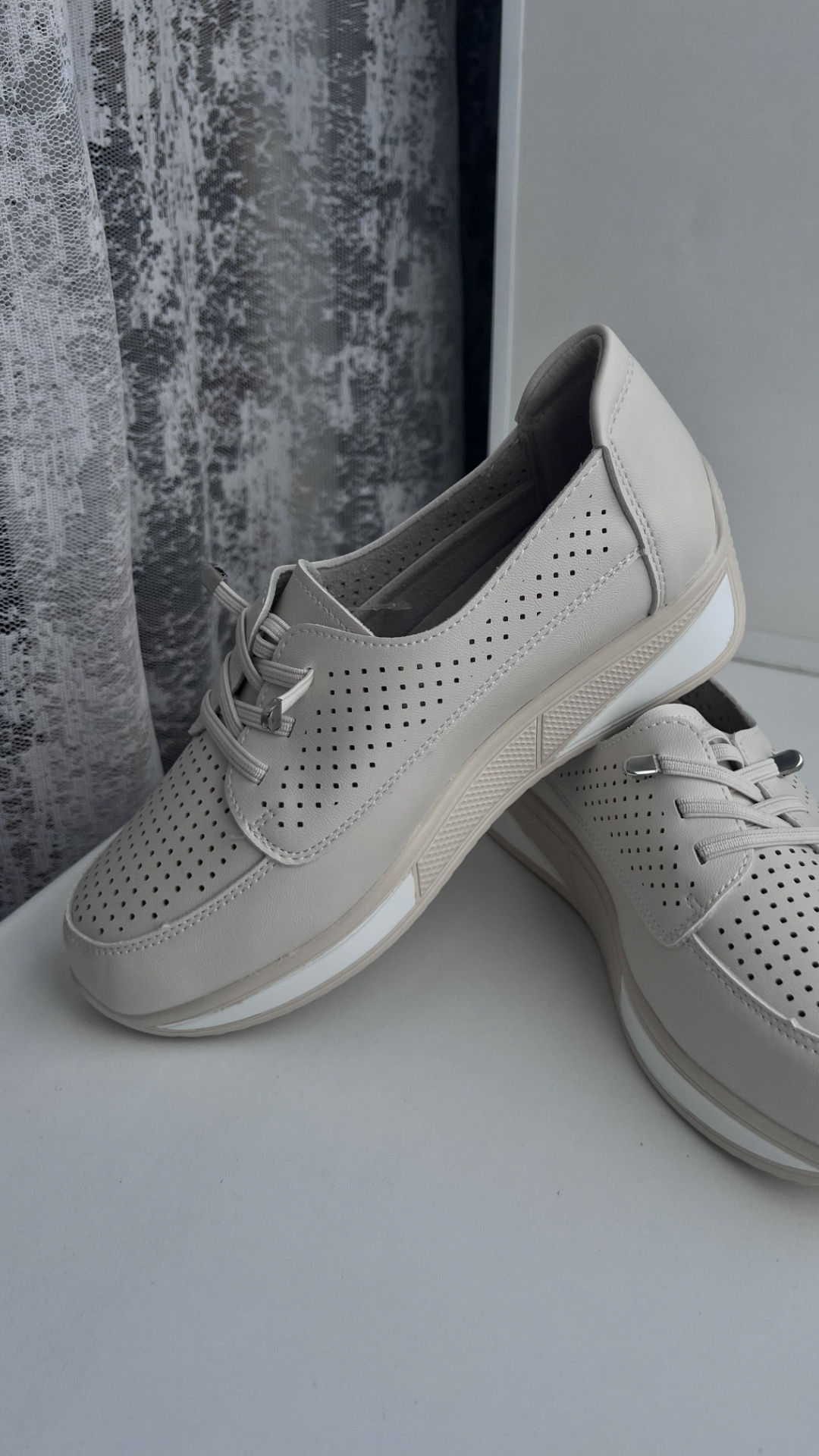 Cinematic slow motion shot of a lightweight beige casual sneaker gently floating down toward a so...
