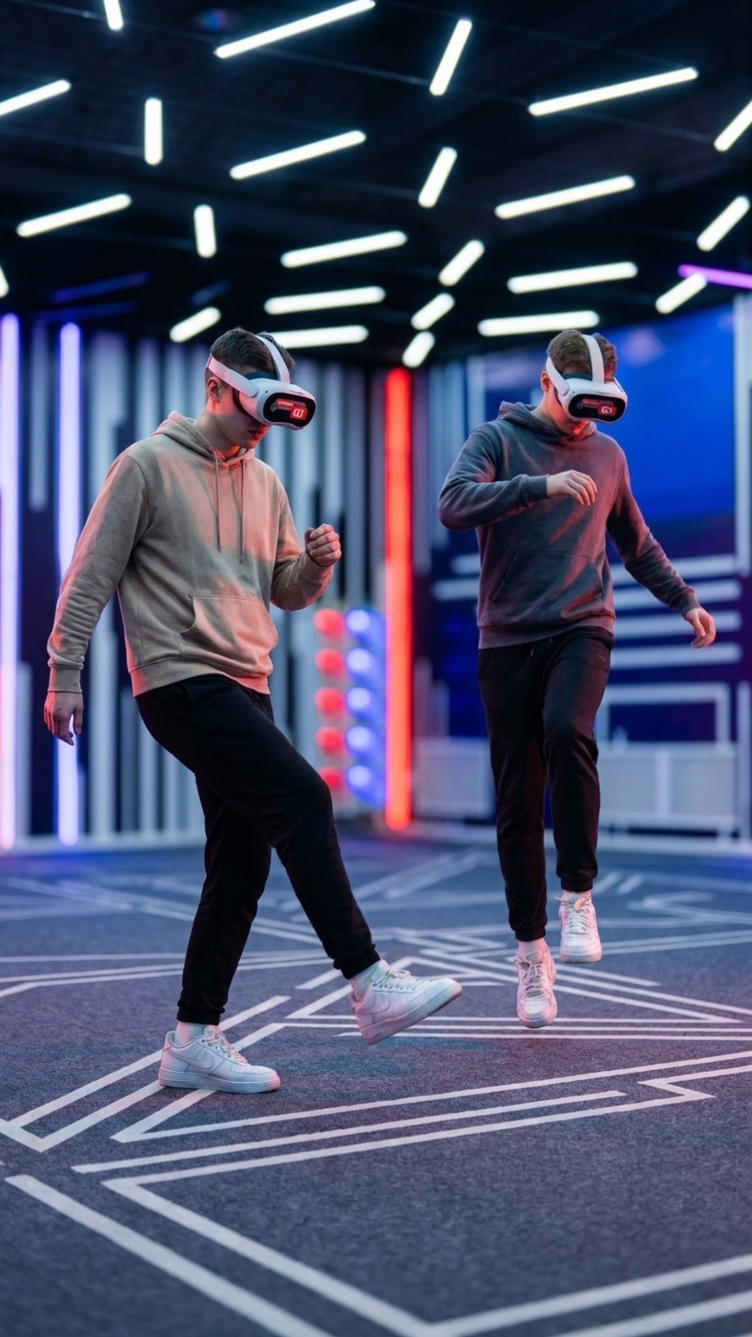 The same two young men are now revealed, wearing sleek virtual reality headsets, still actively p...