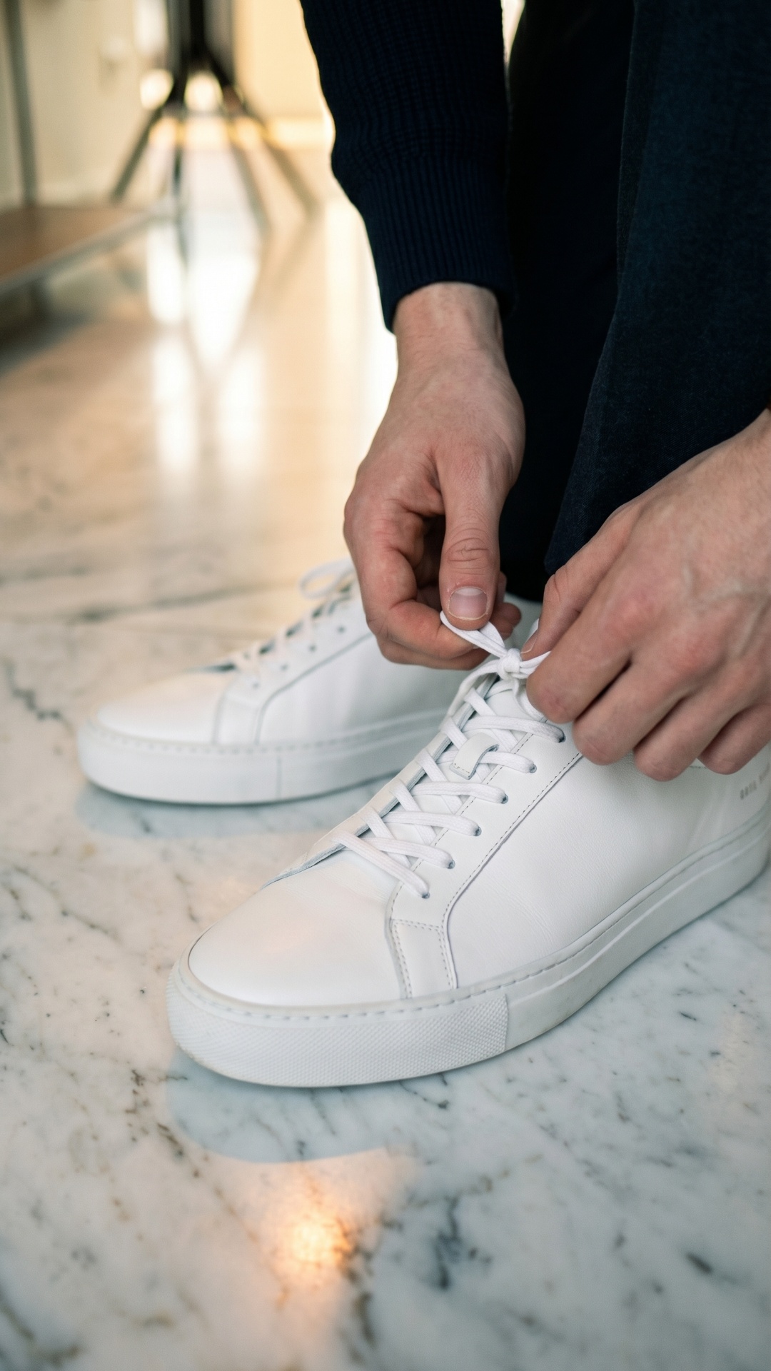 close-up of hands untying premium sneakers slowly, slight tension in fingers, realistic micro mov...