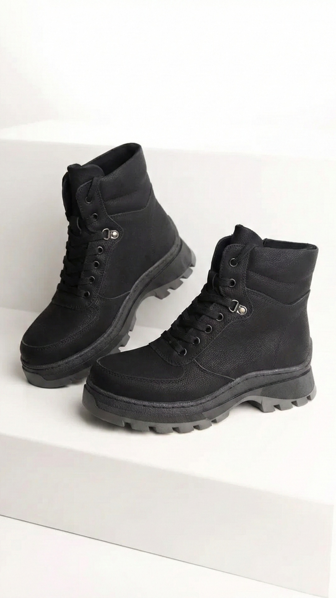 A vertical 9-second cinematic video showing premium winter leather boots in a dark studio, remini...